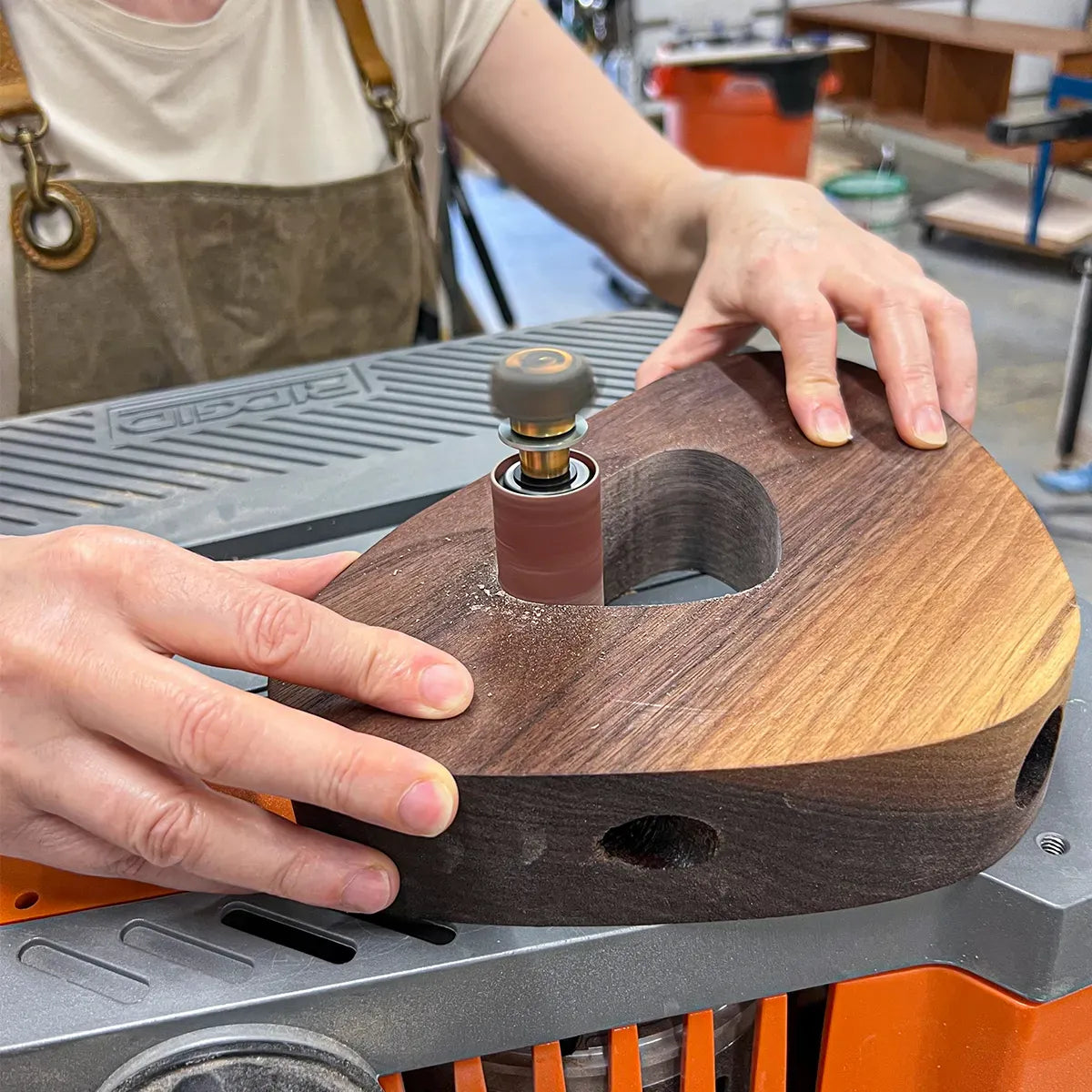 Asha shaping a walnut furniture piece with a spindle sander in the Dovetails & Stitches Birmingham studio.