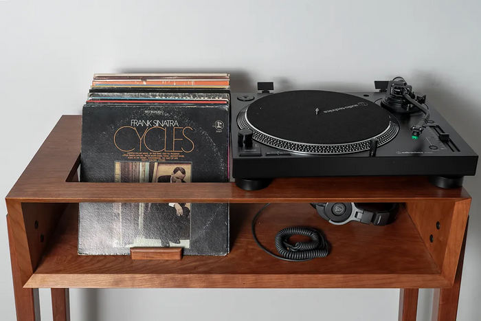 Mid-century modern cherry record player stand holding a turntable, headphones, and a collection of vinyl records with Frank Sinatra’s “Cycles” album in front.