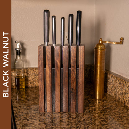 The Chain knife block in black walnut holding five kitchen knives on a countertop