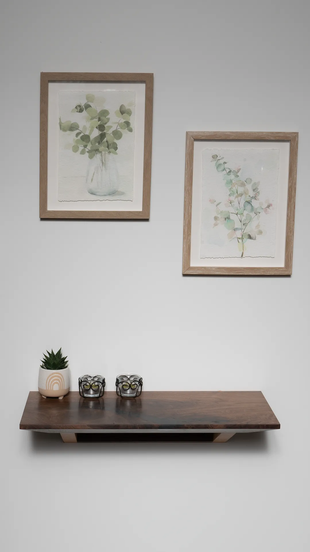 Ripple floating console table in walnut and beech mounted on a wall beneath framed artwork