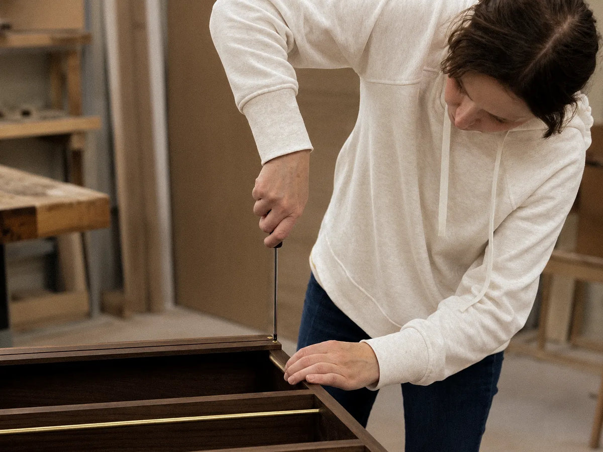 Driving a screw by hand to assemble a walnut piece at the bench