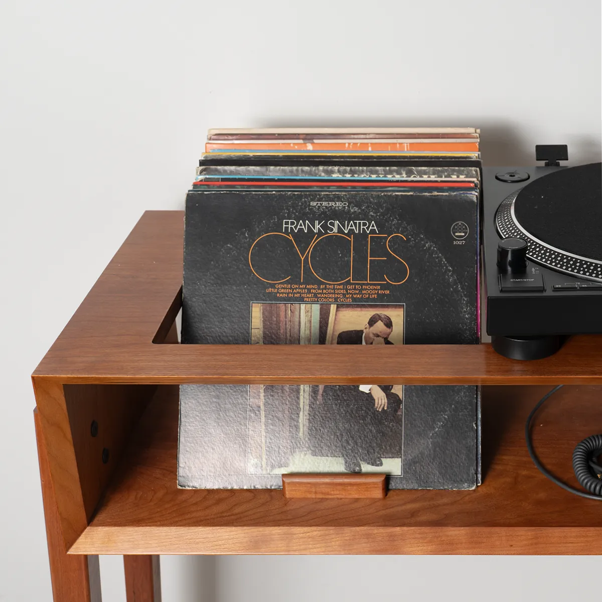 Detail of upright vinyl record storage area on She’s a Lady cherry record player stand, showing album display and mid-century modern design