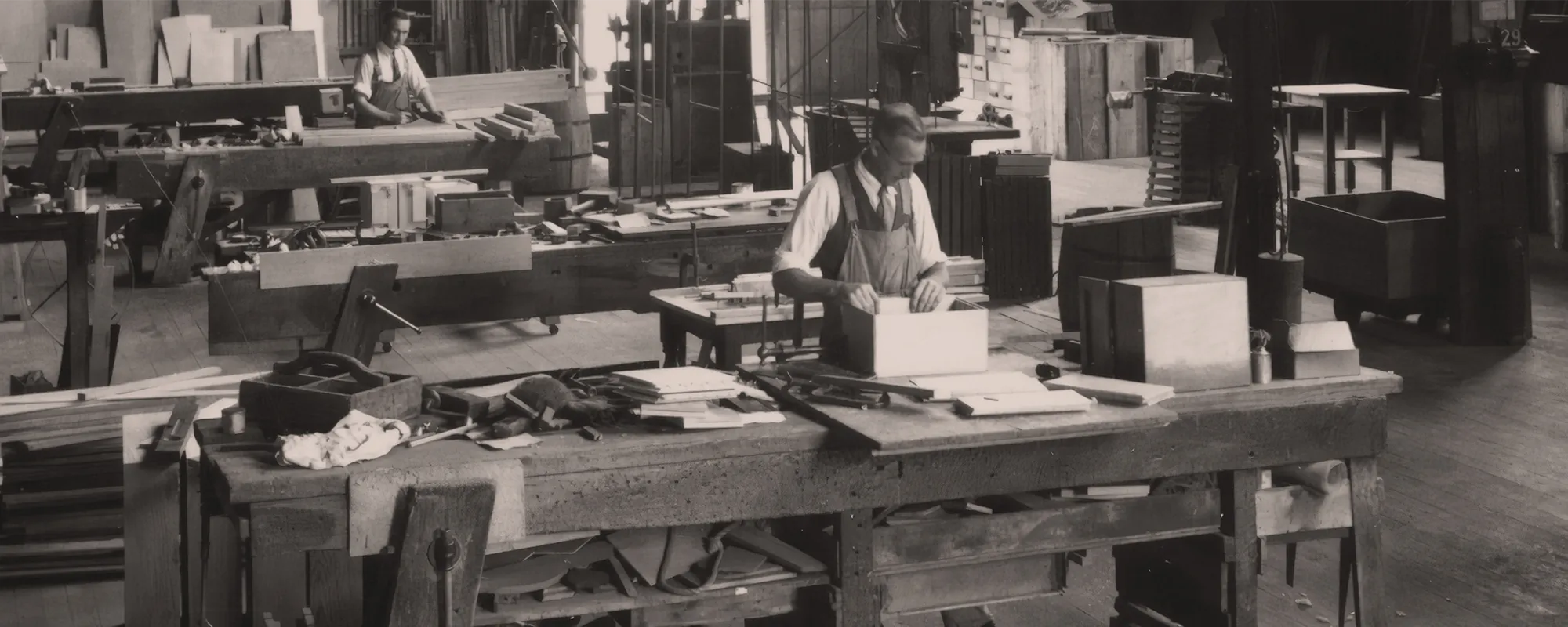 Vintage woodworking studio with craftsman at work, honoring the multi-generational roots of Dovetails and Stitches
