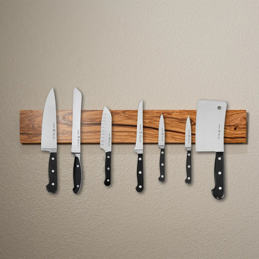Wall-mounted olive wood magnetic knife bar holding seven kitchen knives