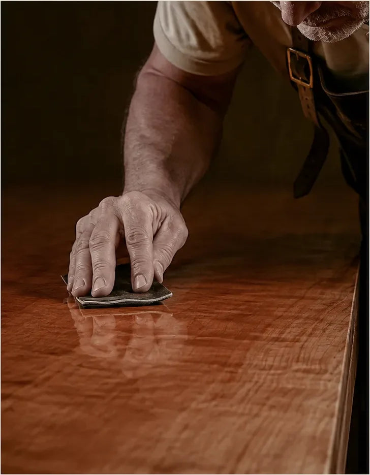 A hand sanding the cured finish of the Ania desk