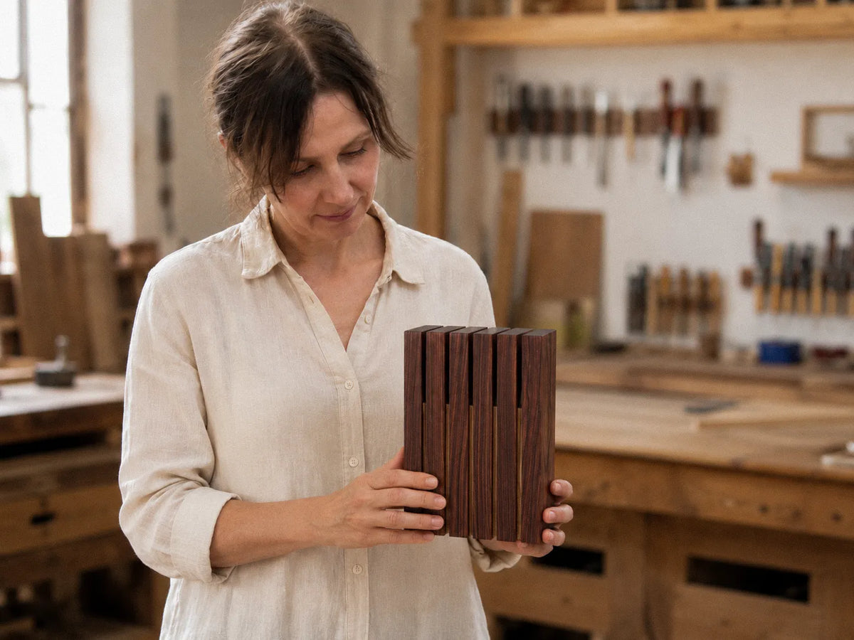 Asha holding a finished rosewood knife block in the workshop