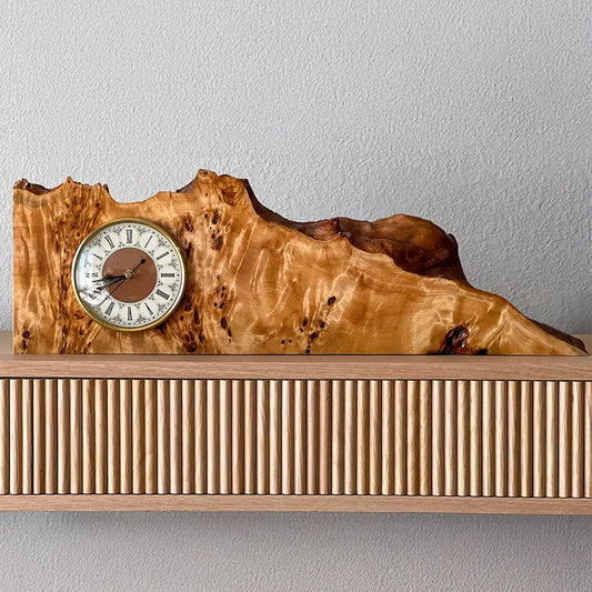 Front view of a handcrafted mappa burl mantel clock from the Signature Series, showing swirling grain and brass clock face.