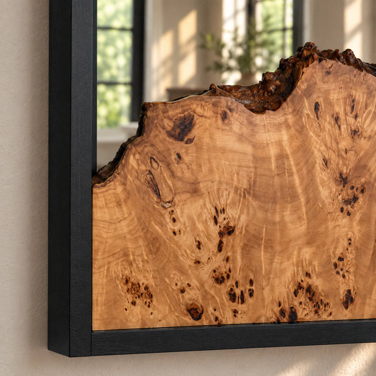 The narrow black frame of the burl wood mirror seen from the side, showing its three inch depth and beautiful burl grain.
