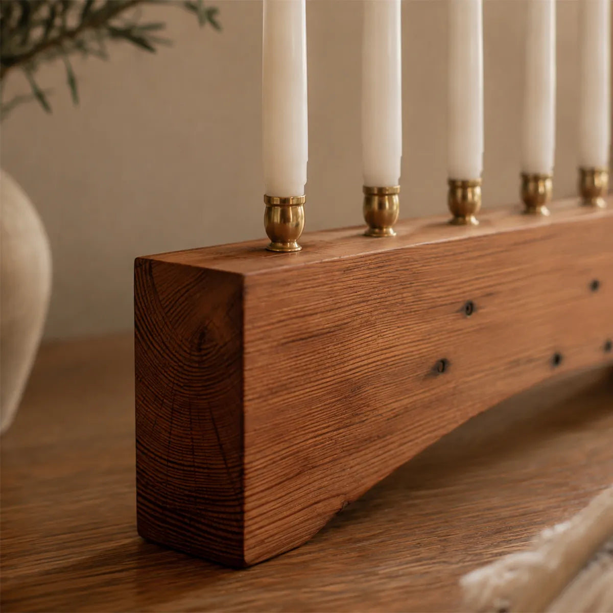 Detail of the 500 Miles menorah in reclaimed heart pine, showing the tight end grain, brass candle cups with cream tapers, and preserved nail holes along the wood.