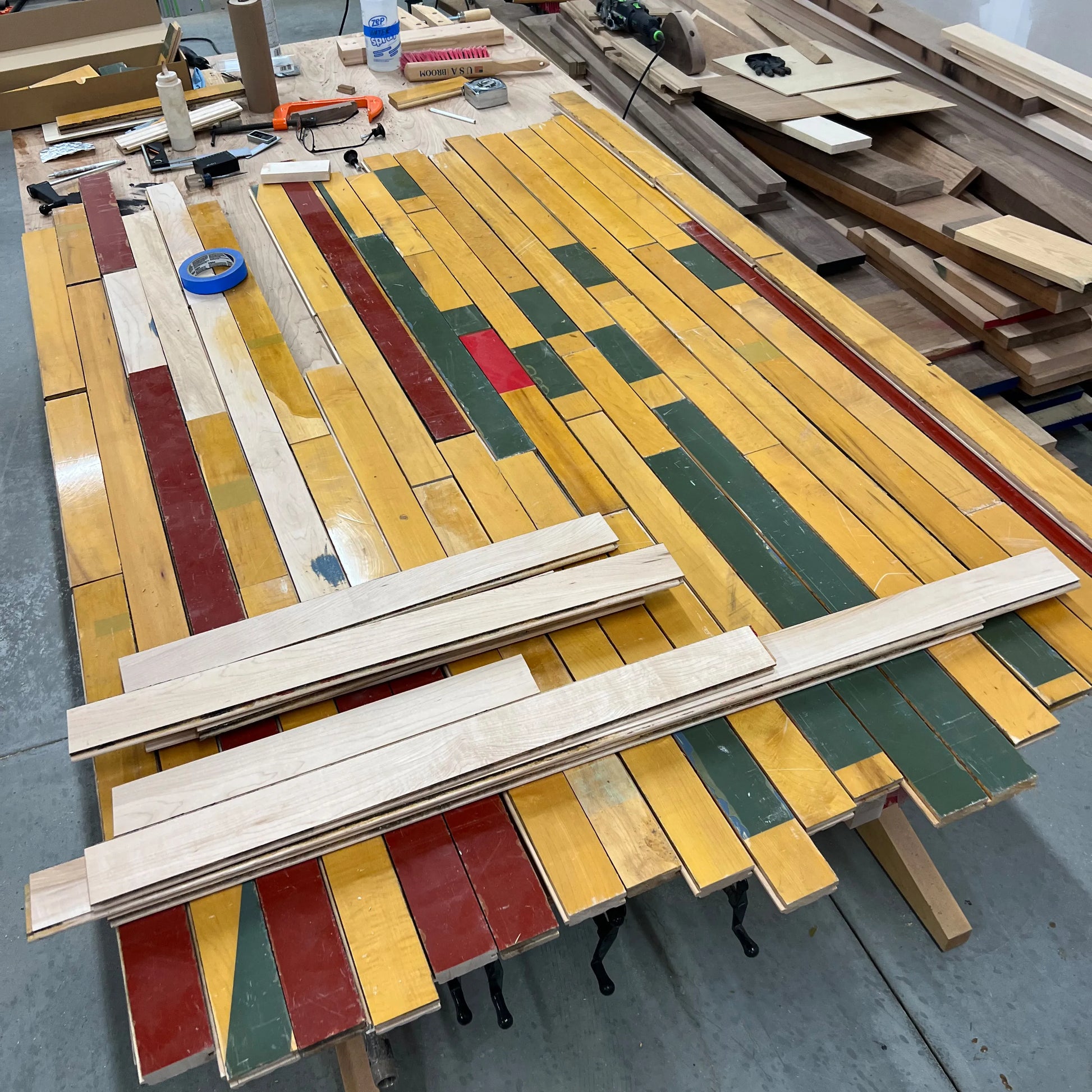 Salvaged gym floor maple boards with original painted court lines before refinishing for a custom reclaimed wood table