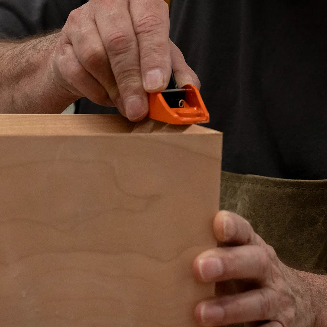 Richard hand-cutting the counter bevel on a cherry mid-century modern Ania desk, showcasing craftsmanship and detail in custom woodworking