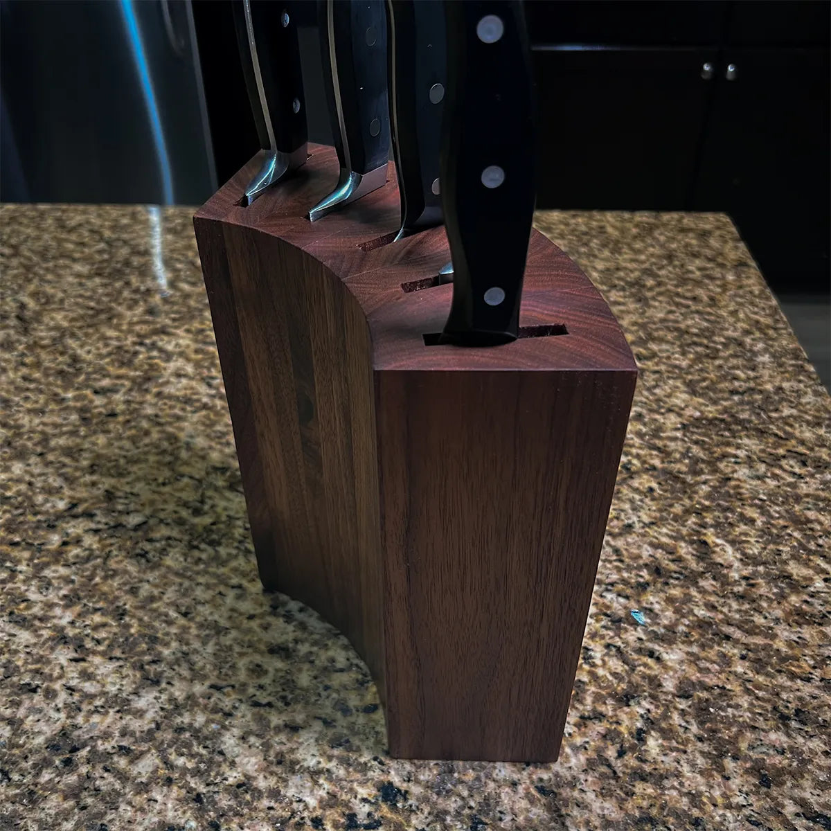 Solid walnut knife block with coopered curved sides and furniture-grade finish.
