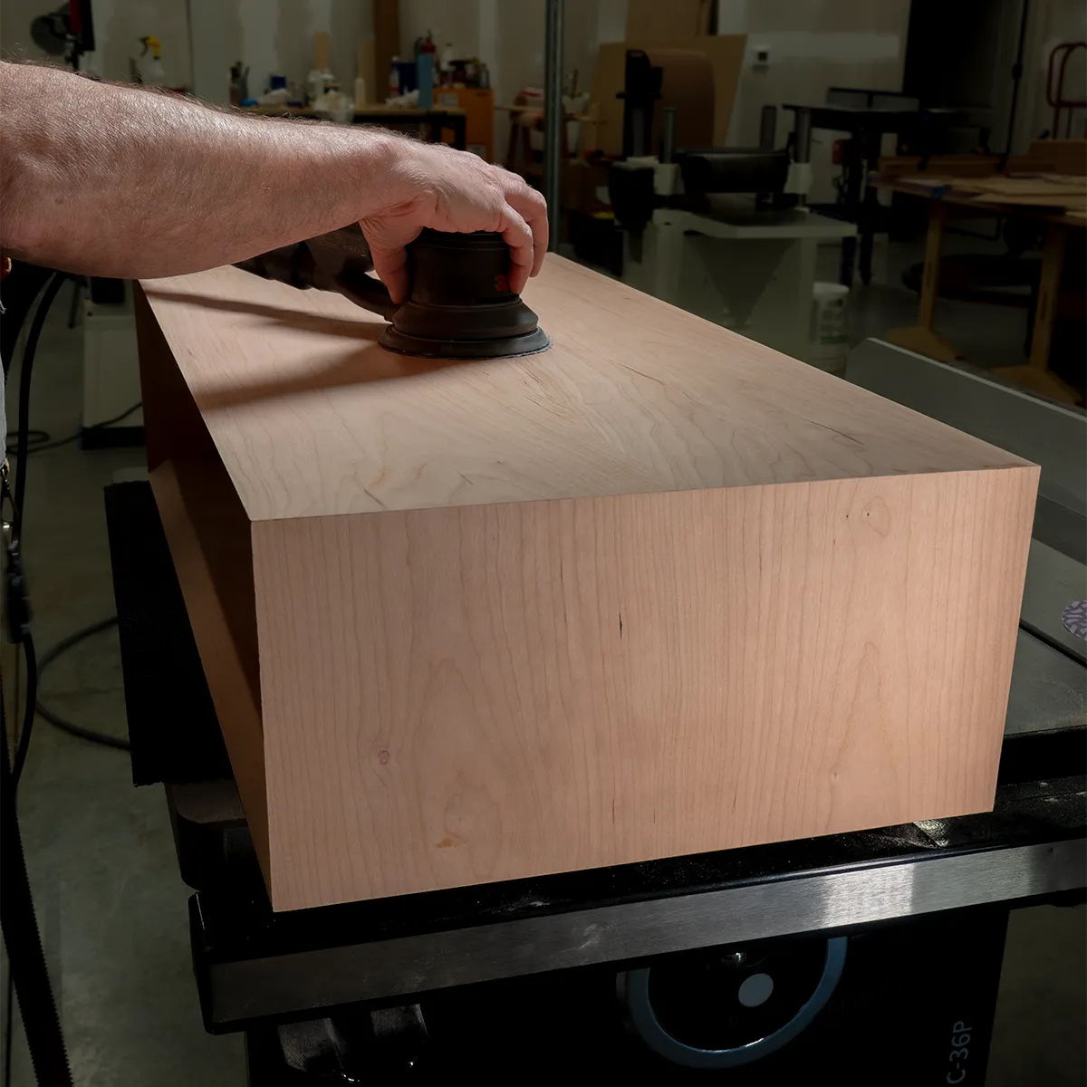 Sanding the solid cherry cabinet for She’s a Lady record player stand, showing handcrafted mid-century modern vinyl storage furniture in progress