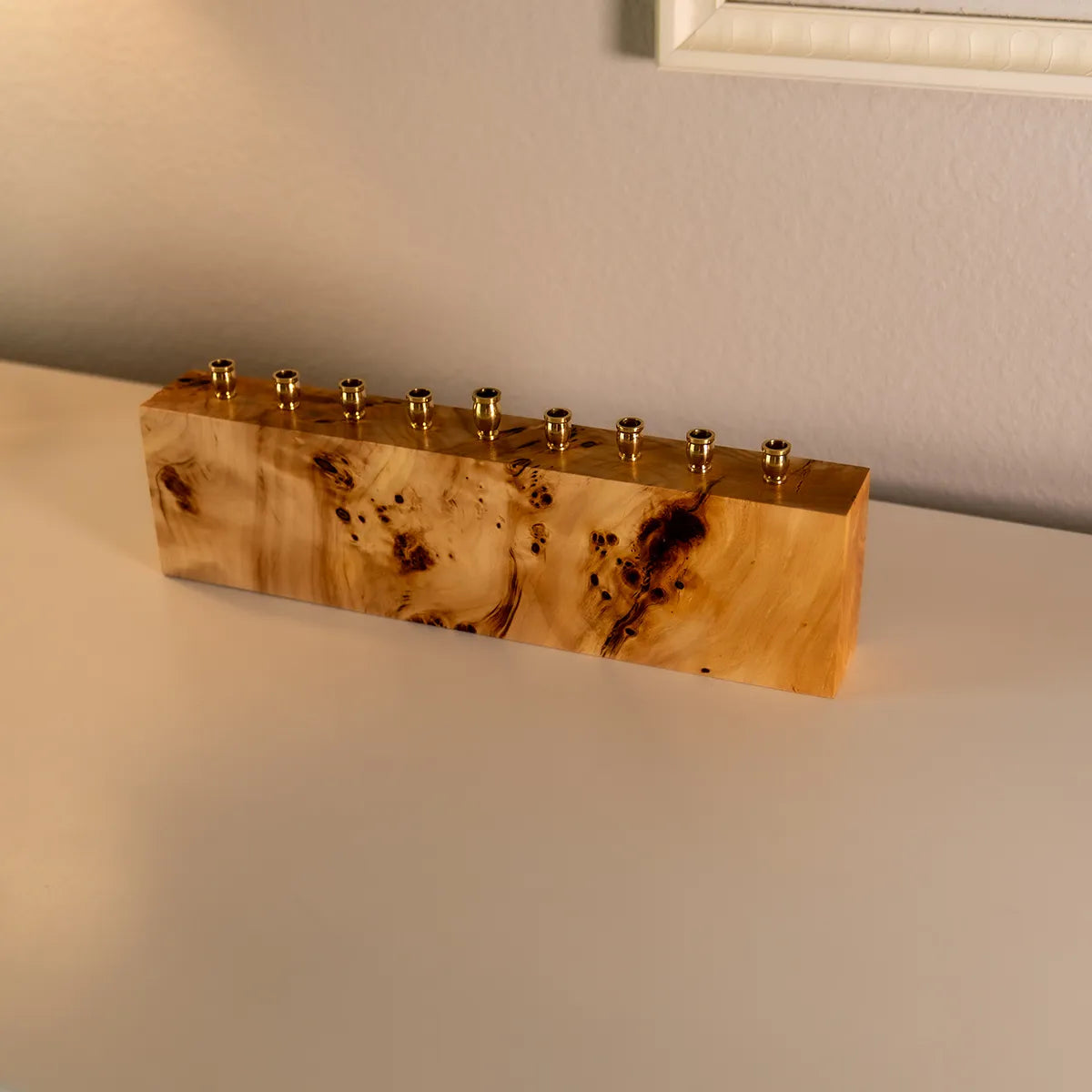 Solid burl menorah made from mappa burl with brass candle cups, shown from a side angle to highlight the unique grain and handcrafted details.