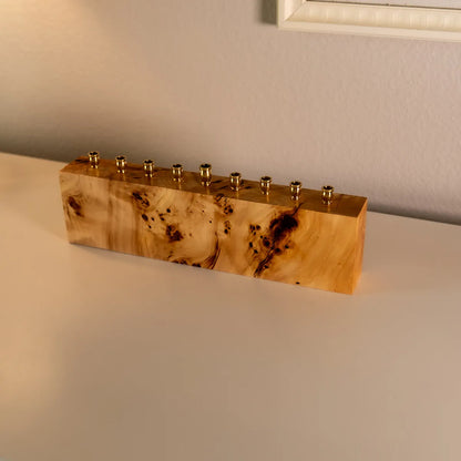 Solid burl menorah made from mappa burl with brass candle cups, shown from a side angle to highlight the unique grain and handcrafted details.