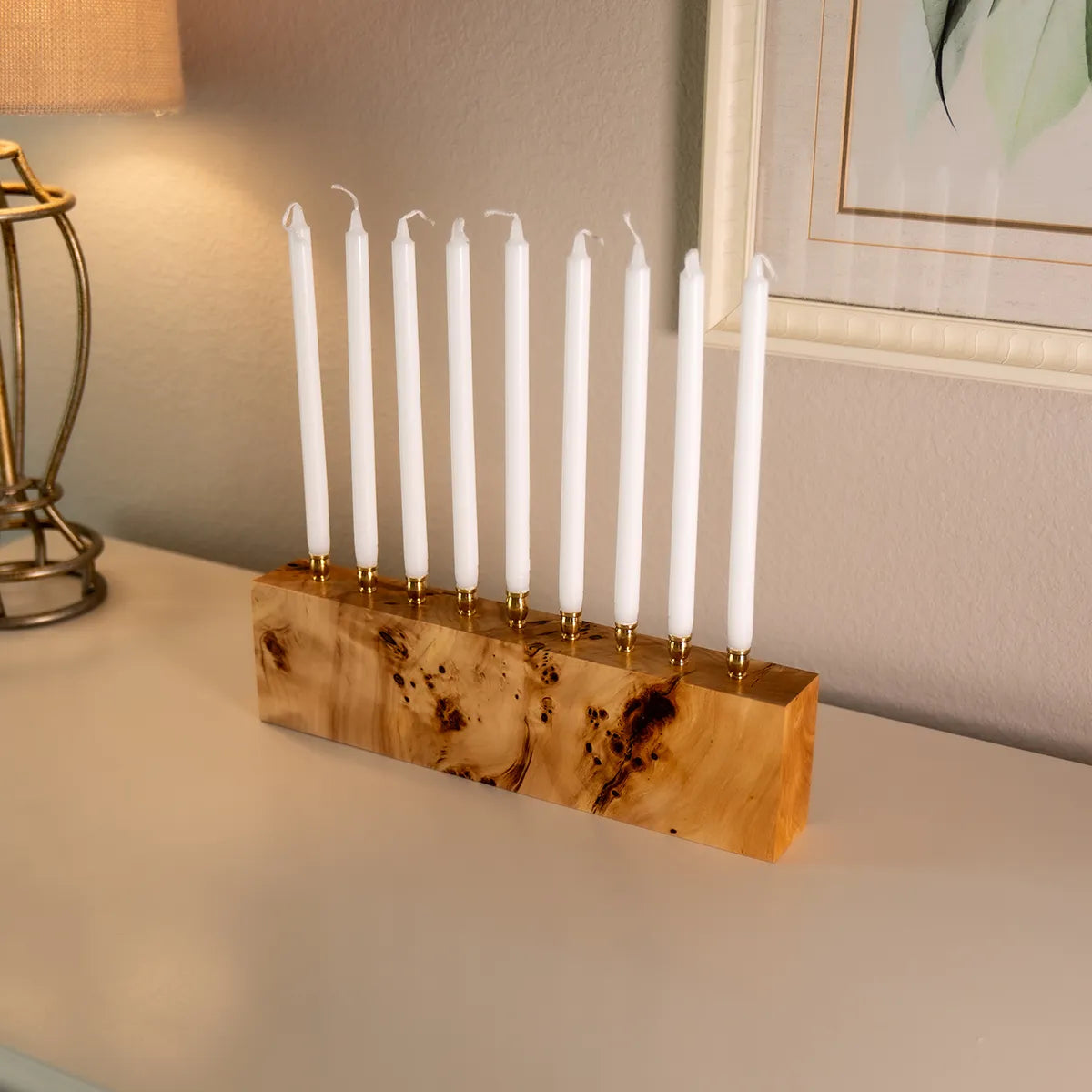 Solid mappa burl menorah with brass candle cups, displayed with white Hanukkah candles, highlighting the wood’s swirling grain and handcrafted quality.