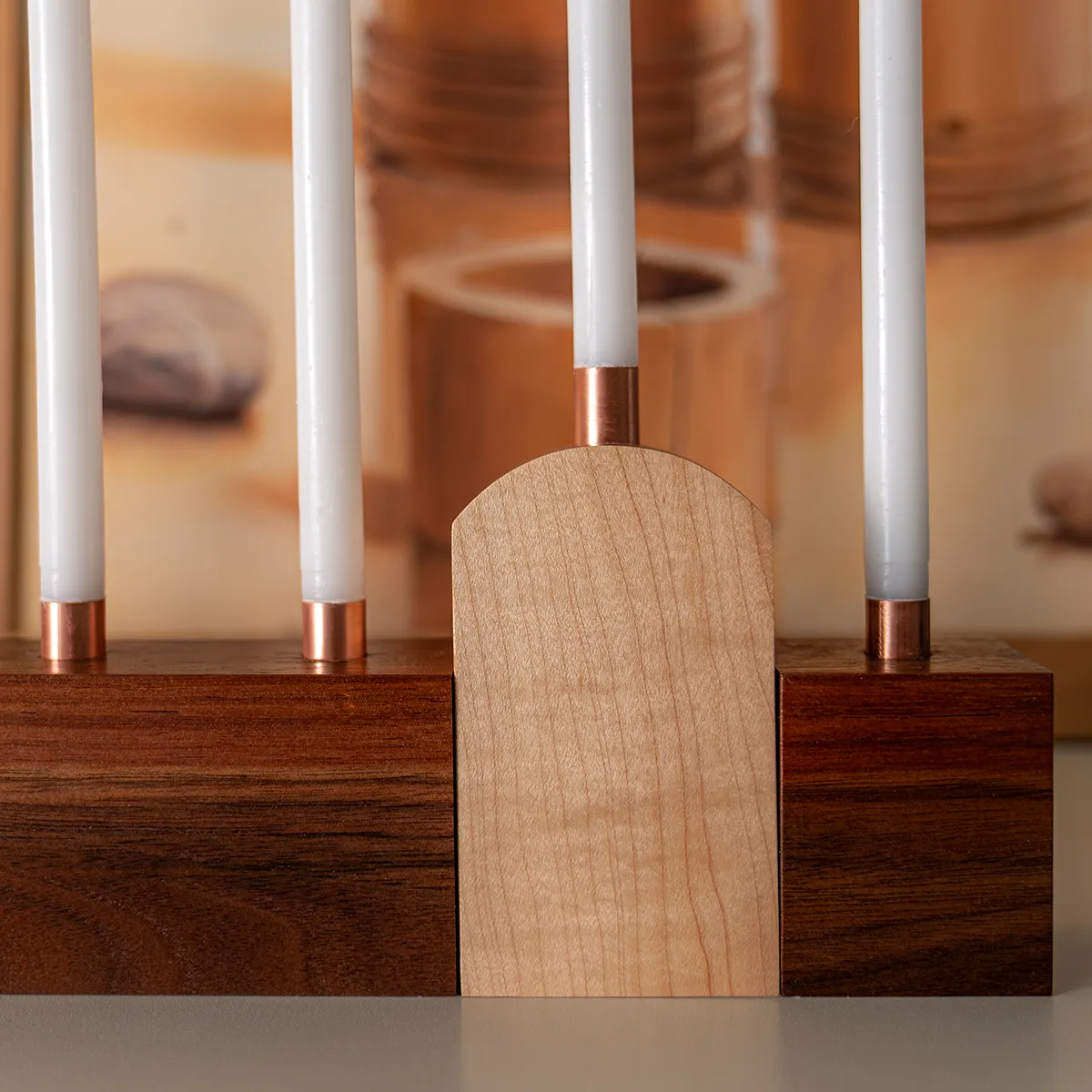 Close-up of polished copper candle holders in a a walnut and maple modern menorah design