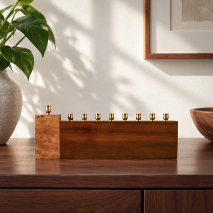 Piece of My Heart handmade Hanukkah menorah in solid walnut with a raised Mappa burl shamash block and eight brass candle cups, on a wood sideboard