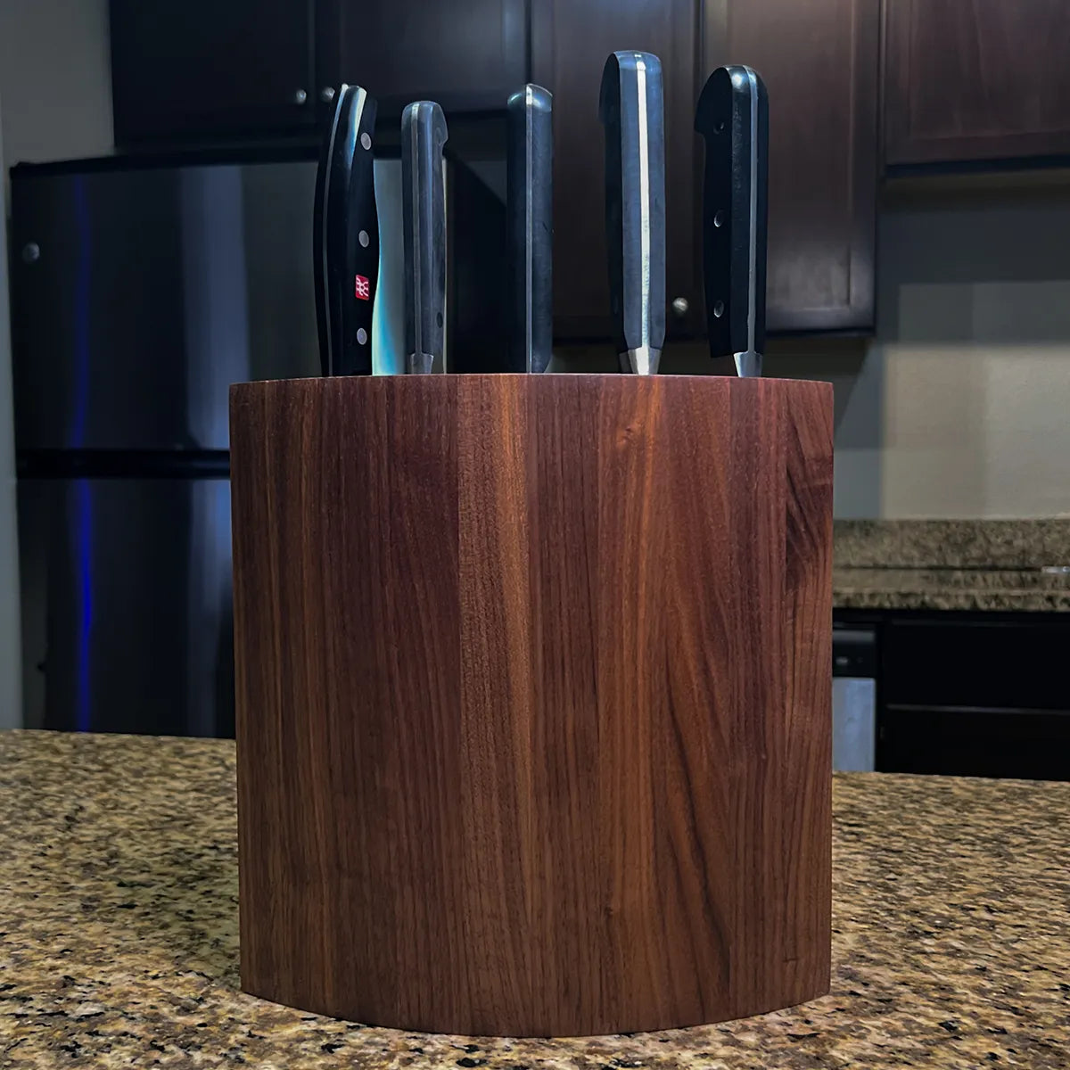 Handcrafted walnut knife block showing five depth-tuned knife slots in a curved mid-century design