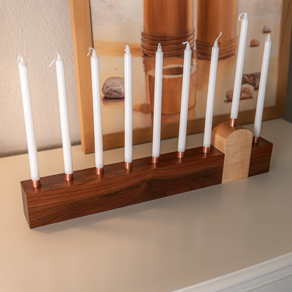 Side view of modern wood menorah with copper candle cups and maple shamash